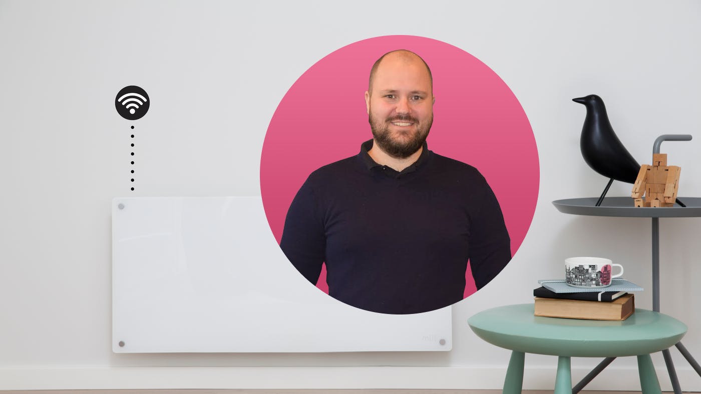 Philip Bryn-Haugland op een roze achtergrond met een Mill-verwarming en twee bijzettafeltjes met decoratie erachter